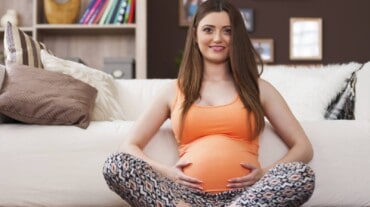 A pregnant woman with arthritis sitting with her hands on her belly