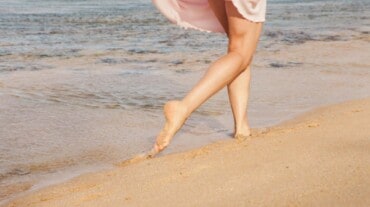 A woman with cracked heels running on a beach