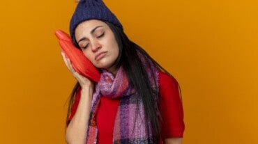 A woman using heating pad to manage joint pain during period